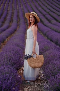 charming Young woman with a hat and white dress in a purple lavender field. LIfestyle outdoors. Back view.