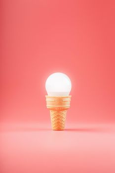Light bulb ice cream in a waffle Cup on a pink background. Minimalistic concept of a sweet idea.