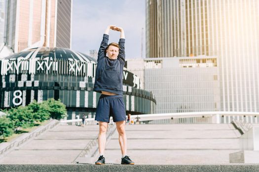 Young athlete man runner running up and down on city stairs in summer on morning run, background urban city street. Sports training. Fitness cardio workout in fresh air, walk outside.