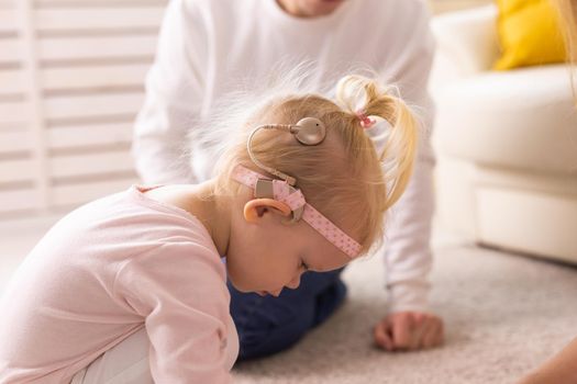 Kid with cochlear implants playing with toys at home. Deafness and medical technology