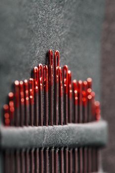 Sewing needles of different sizes in a set of red on a black background. Macro
