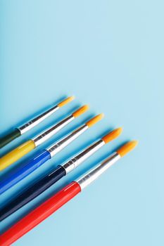 Multi-colored paint Brushes on a blue background. Free space