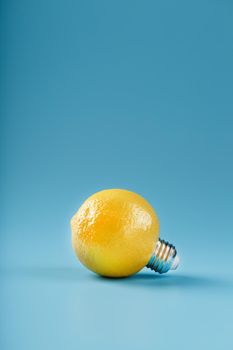 The light bulb is like a lemon on a blue background. Lemon fruit with a light bulb cartridge. Concept of an idea