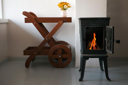 Cozy Bright living room interior with fireplace and wooden table. chimney made of metal. relaxing ambiance and room heating.