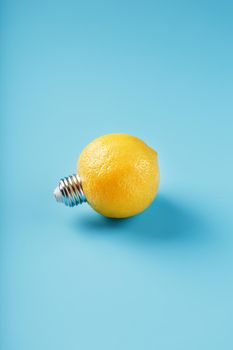 The light bulb is like a lemon on a blue background. Lemon fruit with a light bulb cartridge. Concept of an idea