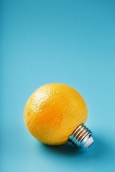 Lemon fruit as a light bulb on a blue background. The conceptual idea. Bright yellow fruit with a light bulb thread