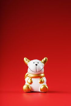 Ceramic Christmas cow bull toy on a red background. Symbol of the new year. Isolate