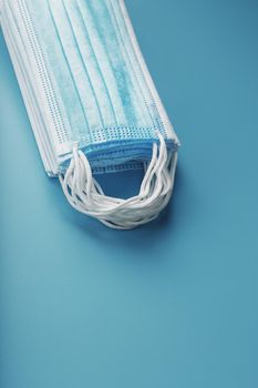 Stack of protective medical masks on a blue background, isolate. Protection against diseases viruses and bacteria, coronavirus, Covid-19, bacteria, pollution, influenza virus.