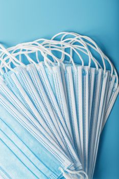 Stack of protective medical masks on a blue background, isolate. Protection against diseases viruses and bacteria, coronavirus, Covid-19, bacteria, pollution, influenza virus.