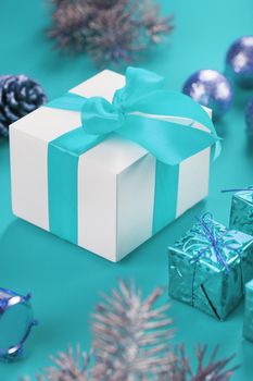 Christmas gift in the form of a white box with a blue bow on a blue background around Christmas decorations. New year's composition of the holiday.