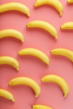 Bright pattern of yellow bananas on a pink background. View from above. Flat lay. Fruit patterns