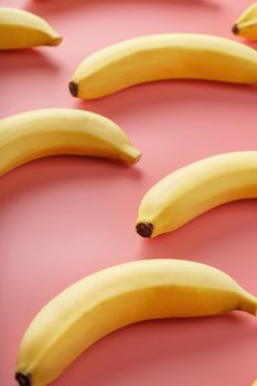 Bright pattern of yellow bananas on a pink background. View from above. Flat lay. Fruit patterns