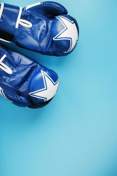 A pair of leather Boxing gloves on a blue background, free space. The concept of fighting and fighting with difficulties.