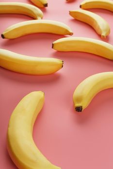 Bright pattern of yellow bananas on a pink background. View from above. Flat lay. Fruit patterns