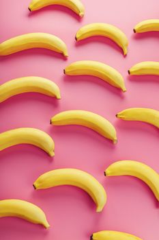 Geometric pattern of bananas on a pink background. The view from the top. Minimal flat style. Pop art design, creative summer concept.