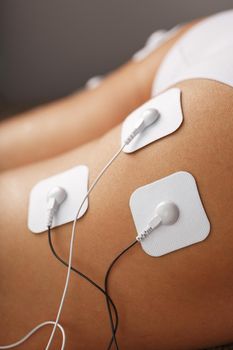 Myostimulation electrodes on the buttocks and legs of a woman in a beauty salon. Rehabilitation and treatment, weight loss. Close-up