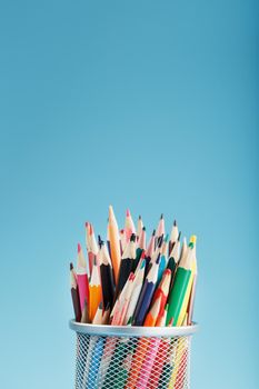 Colorful pencils in a metal jar on a blue background. The concept of creativity, the space