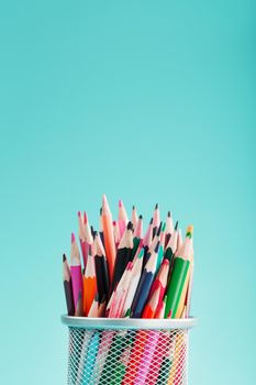 Colorful pencils in a metal jar on a blue background. The concept of creativity, the space