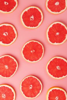 Patterns of slices of juicy grapefruit on a pink background, a beautiful pattern. Top view, full screen