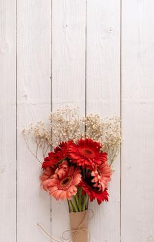 Happy birthday. Red gerbera daisy flowers on white wooden table, flat lay