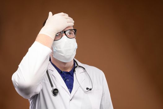 Male Caucasian doctor in white medical uniform shows face palm gesture. Chagrin and disappointment. Copy space.
