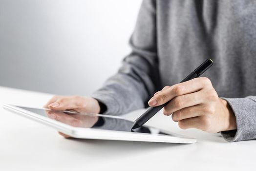 Woman using tablet computer for project management. Close-up of female hand holding pen and touching screen of tablet device. Online stock trading and investing. Mobile smart device in business