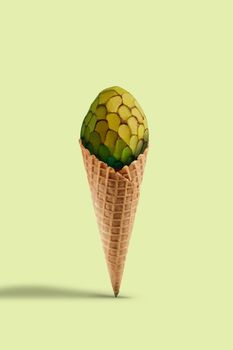 Green cherimoya or sugar-apple in sweet wafer cone against yellow background. Concept of healthy nutrition, food, seasonal harvest of berries and fruits. Close up, copy space