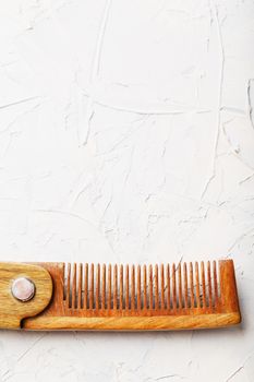 Wooden Sandalwood comb folding on a white textured background. Hair care. Isolate.