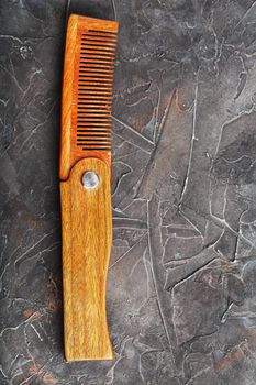 Folding wooden comb on a black background. Close up.