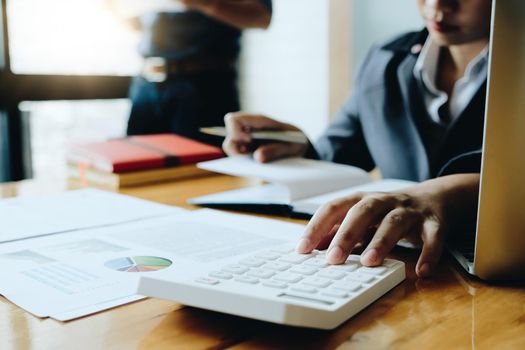 Business woman using calculator for do math finance on wooden desk in office and business working background, tax, accounting, statistics and analytic research concept