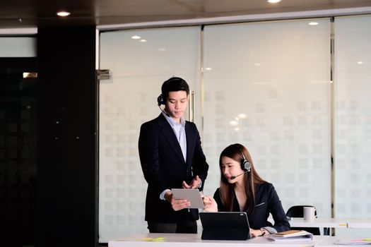 Businessman supervisor training work to businsswoman in call center office.