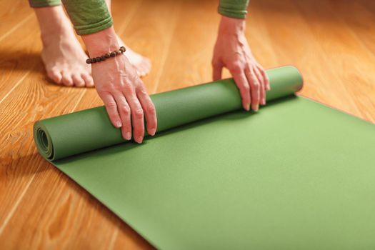 A woman collects a green mat after a yoga class.