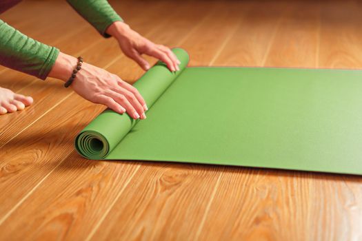 A woman collects a green mat after a yoga class.