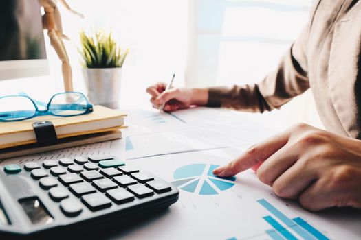 Close up of accountant hand holding pen working on calculator to calculate business financial reports, accountancy document at office, business financial concept