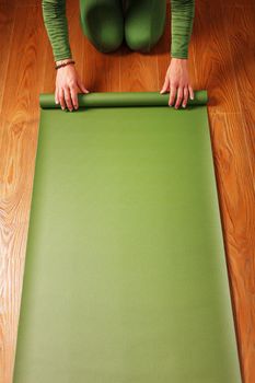 A woman rolls out a green mat before a yoga class.
