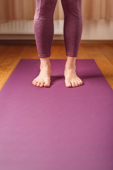 Legs and hands of a woman on a yoga mat practicing asanas. A healthy lifestyle at home in isolation.