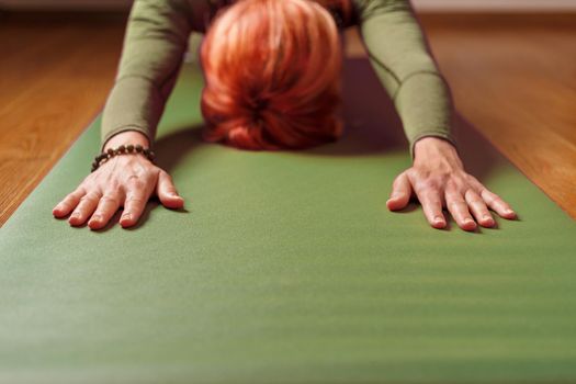 A girl does yoga in Astana on a green mat. Healthy lifestyle, asanas and meditation practices