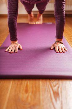 Legs and hands of a woman on a yoga mat practicing asanas. A healthy lifestyle at home in isolation.