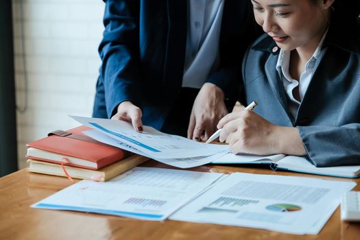 Close up of business people analyzing data from financial documents while working in the office.