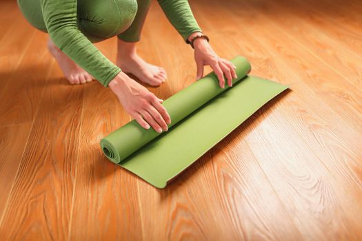 A woman collects a green mat after a yoga class.