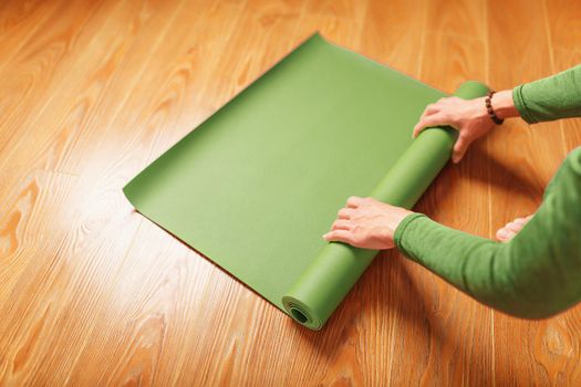 A woman rolls out a green mat before a yoga class.