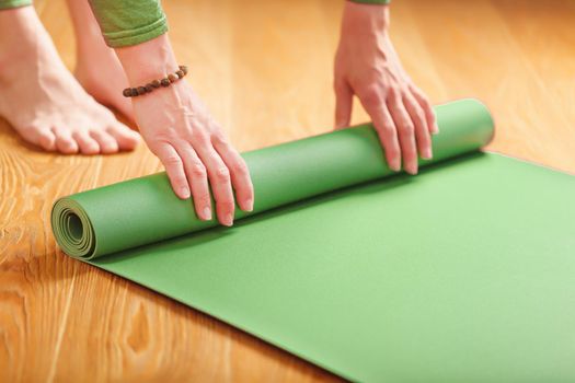 A woman rolls out a green mat before a yoga class.