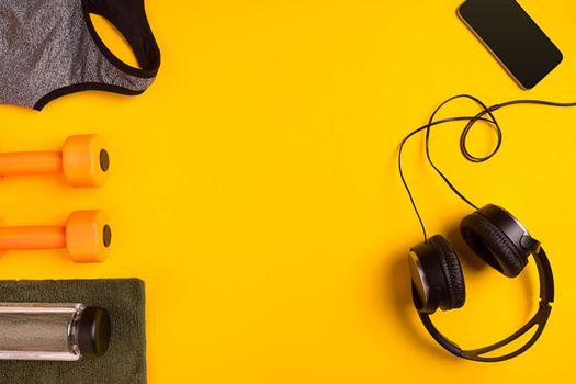 Athlete's set with female clothing, dumbbells and bottle of water on yellow background. Top view. Still life