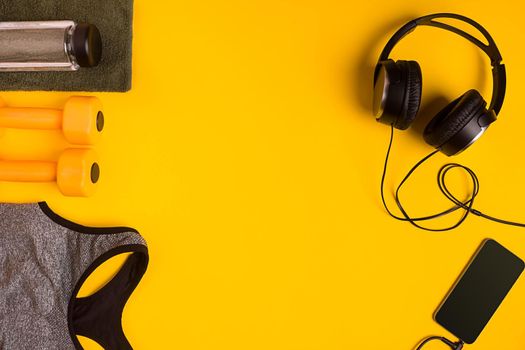 Athlete's set with female clothing, dumbbells and bottle of water on yellow background. Top view. Still life