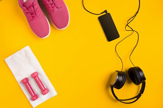 Athlete's set with female clothing, dumbbells and bottle of water on yellow background. Top view. Still life