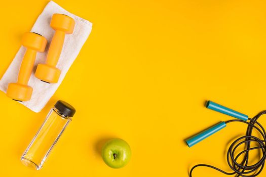 Athlete's set with female clothing, dumbbells and bottle of water on yellow background. Top view. Still life