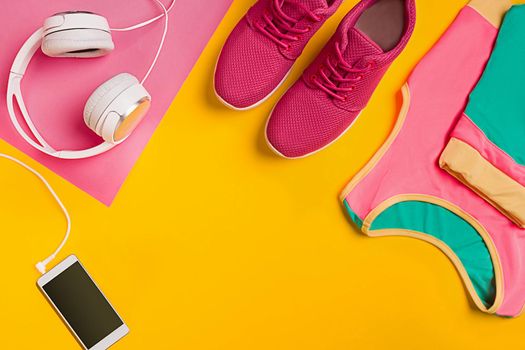 Athlete's set with female clothing, dumbbells and bottle of water on yellow background. Top view. Still life