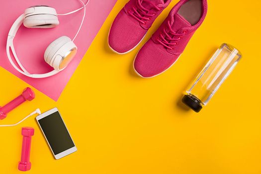Athlete's set with female clothing, dumbbells and bottle of water on yellow background. Top view. Still life