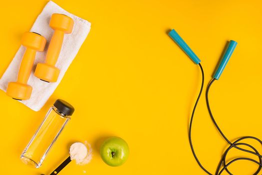 Athlete's set with female clothing, dumbbells and bottle of water on yellow background. Top view. Still life