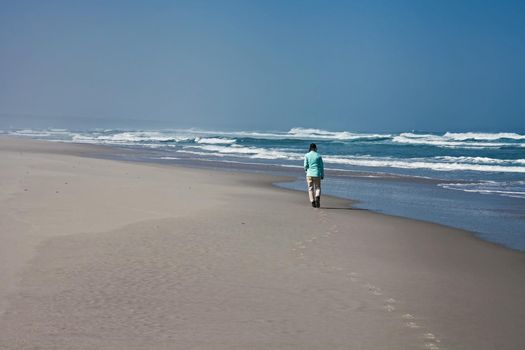 A lone woman walking on a deserted beach